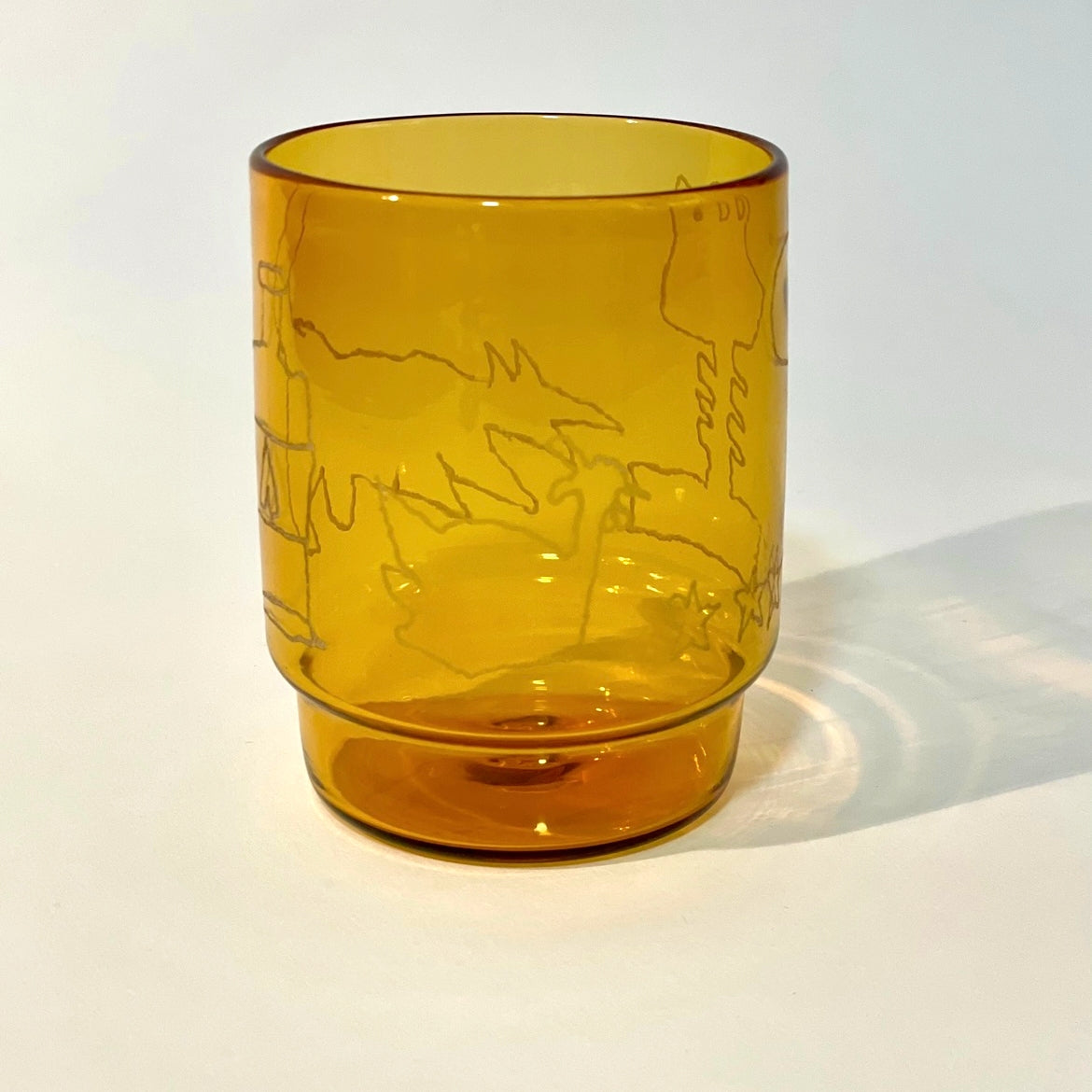 glass tumbler with engraved motifs of a bottle, dog, chicken, flower, stars, sun