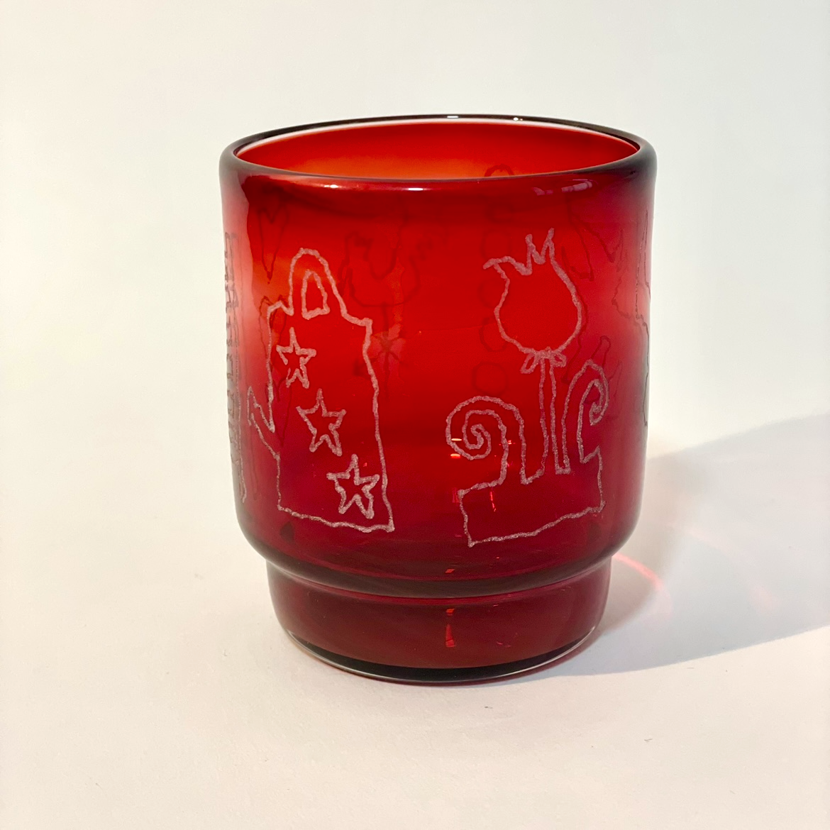 ruby tumbler engraved with watering can, flower, ladder, hound, five coins, hearts, and weather vane motifs