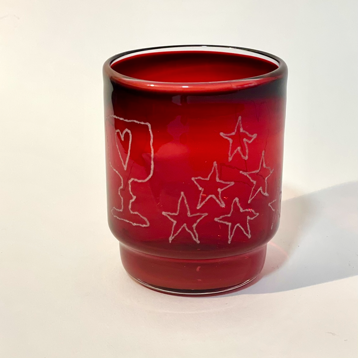 ruby tumbler engraved with a goblet, heart , apple, and moon motifs